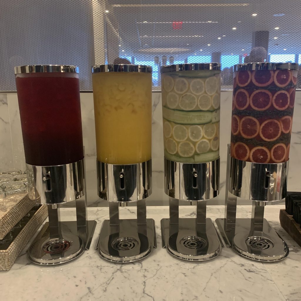 a group of juice dispensers with different fruits