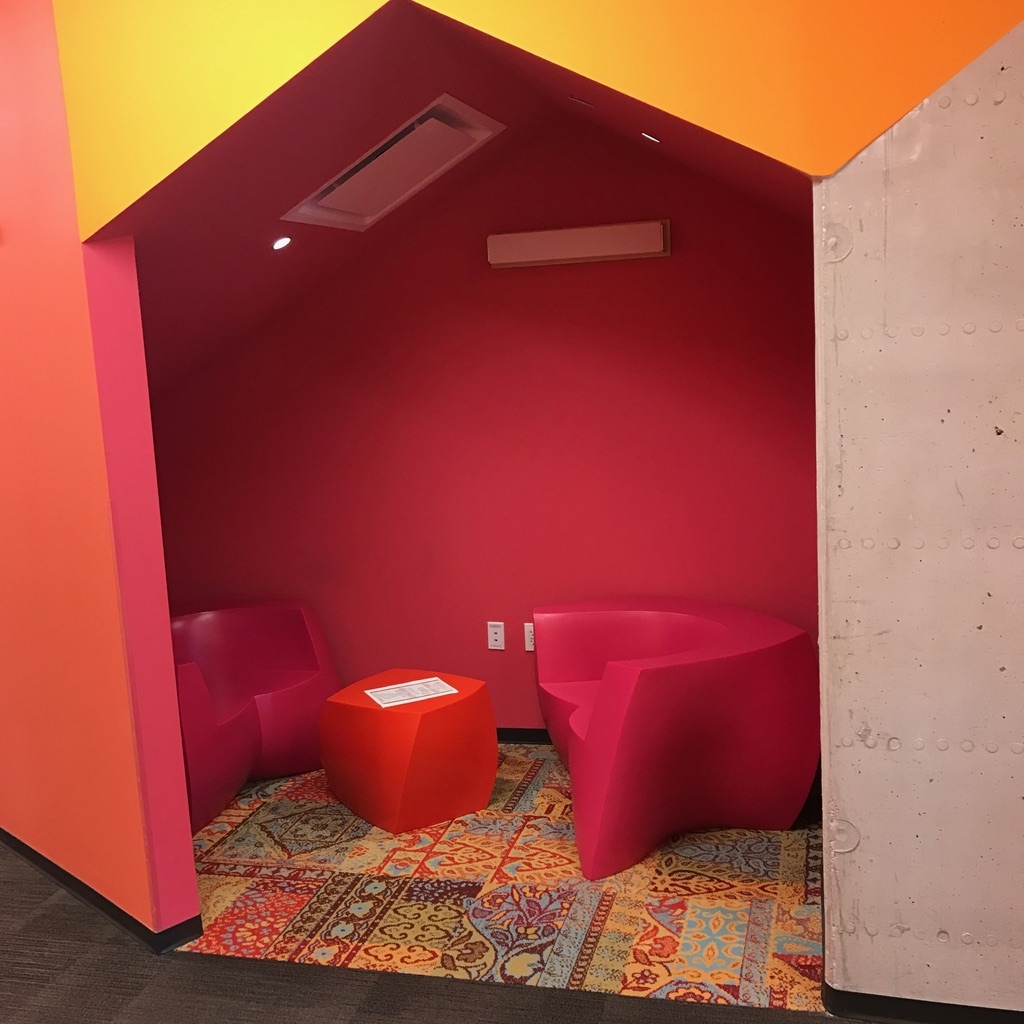 a pink and orange room with a red chair and a table