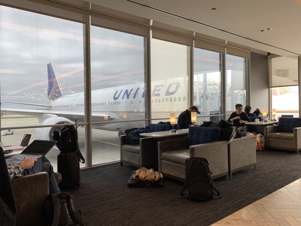 a group of people sitting in a lounge area with a large window